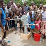 People gathered at a hand pump collecting water