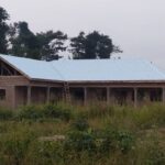 School building under construction with block walls and exposed roof timbers