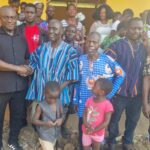 A handshake with a chief in traditional cloth, surrounded by community members and children