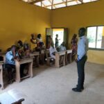 Teacher addressing seated parents and community members in a classroom