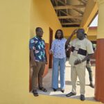 Three people standing on the veranda of a school building
